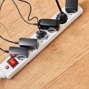 A top down view of a power strip filled with devices plugged into it. This could cause a power surge under the right circumstances.