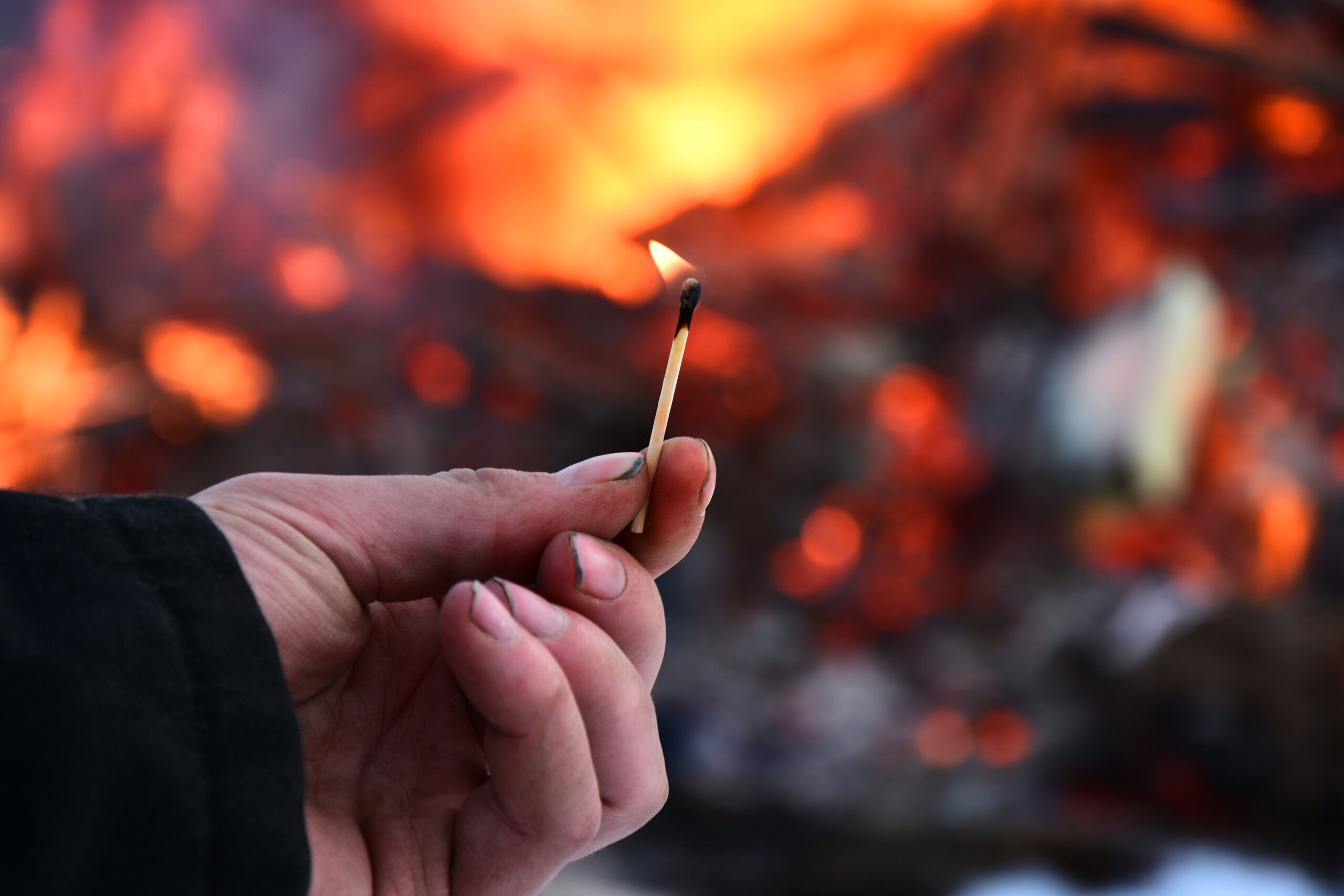 Person holding match behind a fire